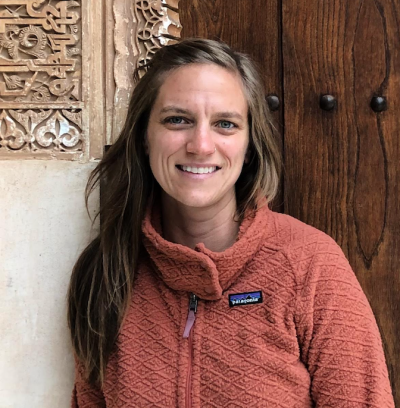 Shelly Annameier, licensed marriage and family therapist, smiling, wearing a light rust colored fleece jacket and leaning against a wall