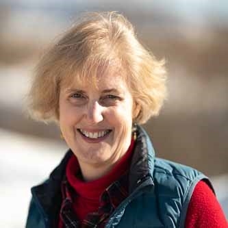 Jennifer Dunkle, licensed professional counselor, outdoors, smiling, wearing a flannel shirt, red sweater, and blue puffy vest