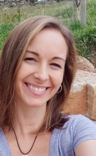 Jackie Johnson, licensed professional counselor, smiling, outdoors, taking a selfie with a large rock, grass, and trees in the background