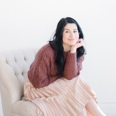 Melissa Londoño Connally, PhD, licensed clinical psychologist, wearing sweater and skirt, smiling, sitting in chair with head resting on the palm of her hand