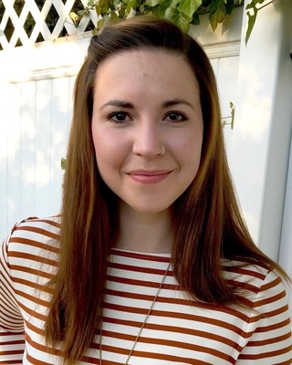 Annie Hennig, licensed marriage and family therapist, outdoors, wearing a striped shirt, standing near a white fence.
