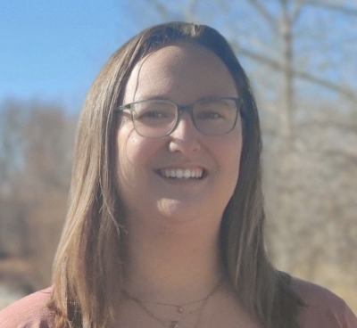 Rachel Berglund, licensed marriage and family therapist, smiling, wearing glasses, standing outdoors with the sun shining