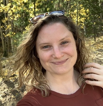 Cassie Thomas, licensed professional counselor, smiling, outdoors with sunlight visible through the trees