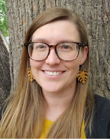 Jana Carson, licensed marriage and family therapist, smiling, wearing glasses, and standing outdoors next to a tree