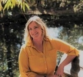 Melissa Blatnik, licensed professional counselor, licensed addiction counselor, smiling, sitting by the Poudre River
