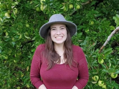 Alyssa Anderson, licensed professional counselor, outdoors, smiling with dark hair and a red sweater. And a hat.