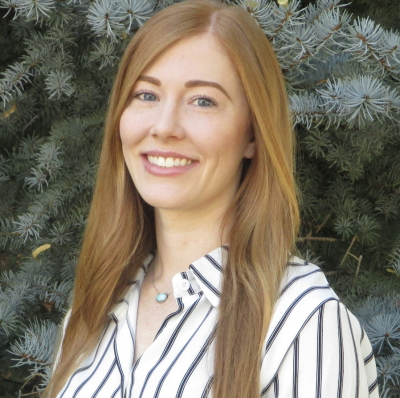 Brandi Wright, licensed professional counselor candidate, standing outdoors in front of an evergreen tree