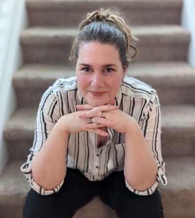 Jolie Beth Boudreaux, licensed professional counselor, smiling, sitting on a staircase with hands under her chin.