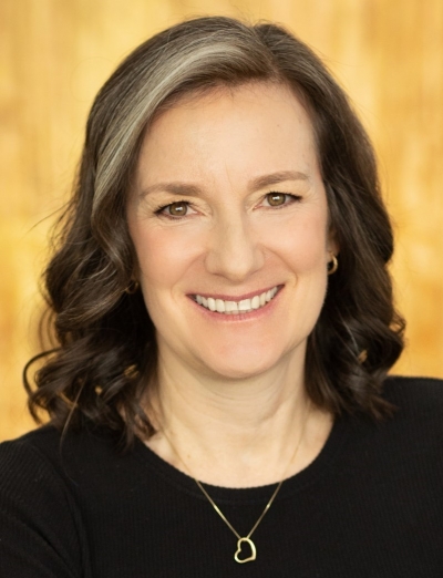 Elizabeth Kittrell, licensed marriage and family therapist, a smiling, middle-aged, Caucasian woman. She has brown and grey hair and brown eyes. She is wearing a black sweater and a thin gold necklace chain with a heart pendant.