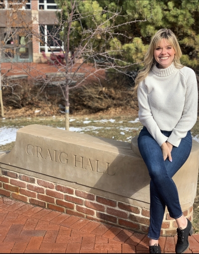 Jenna Rushton, licensed clinical social worker, smiling, wearing a white top and jeans, sitting outdoors