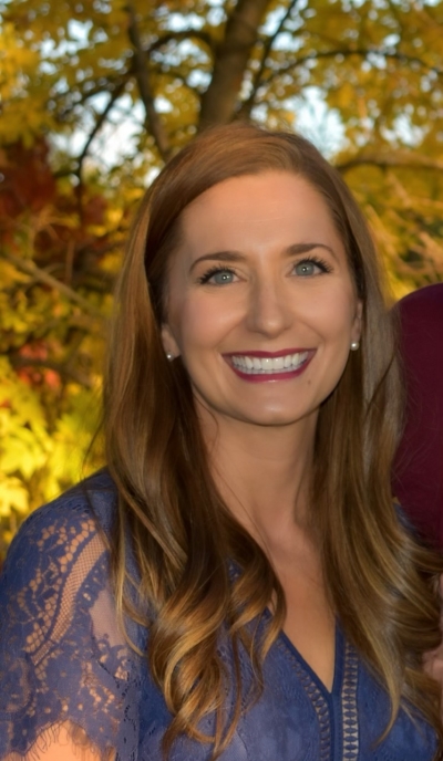 Amanda Ashcraft, smiling, standing in front of a tree.
