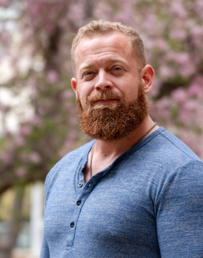 Nicholas Moon, licensed professional counselor candidate, with pink flowering trees in the background