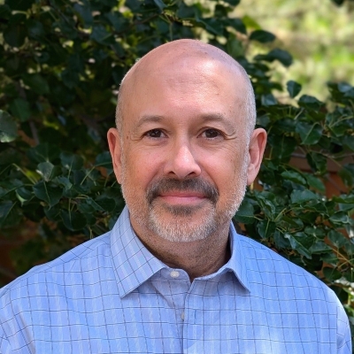 Terry Bohn, licensed professional counselor, wearing a light blue button-up shirt with stripes, standing outdoors with a tree in the background