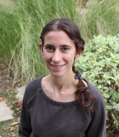 Carla Tungate, licensed clinical social worker, smiling, wearing a brown shirt and standing in front of tall grasses and a bush