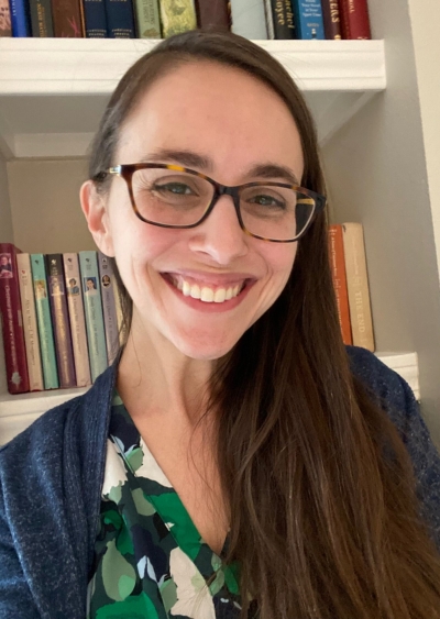 Natasha Alvandi, licensed professional counselor, smiling, wearing glasses, with a bookcase in the background.