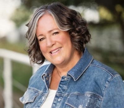 Elizabeth Warson, licensed professional counselor, board-certified registered art therapist, smiling, wearing a white shirt and jean jacket