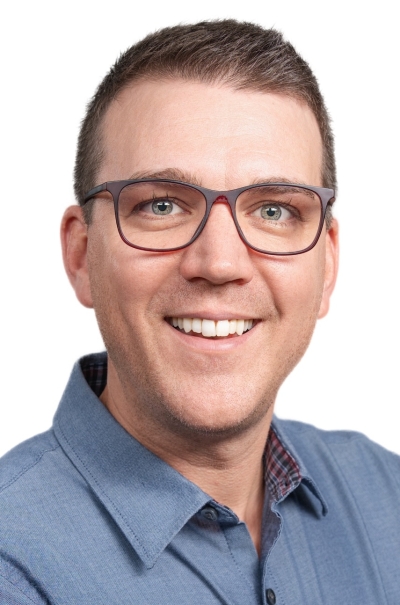 Jake Lohwater, licensed clinical social worker, smiling, wearing glasses, with brown hair and a blue button-up shirt