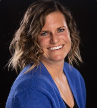 Jeanette Jennings, licensed professional counselor, smiling, with shoulder length brown hair, wearing a black top and blue sweater against a black background