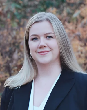 Erin McCarthy, licensed professional counselor candidate, smiling, wearing a white shirt, and dark-colored jacket.