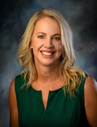 Jennifer Meyer, licensed professional counselor, smiling, with shoulder-length blond hair, a green top, and a blue-grey background