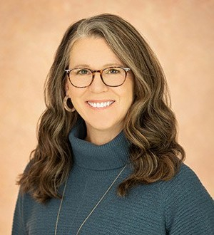 Jennifer Roberts, PhD, smiling, wearing glasses, a turtleneck sweater, and a long necklace
