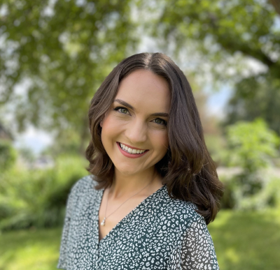 Julia Schafer, licensed clinical social worker, smiling, standing next to a leafy green tree, wearing a green shirt