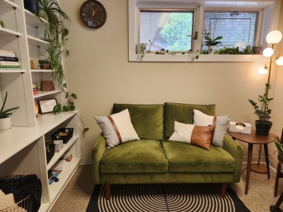 Office with sofa and pillow, window, and large bookcase along one wall.