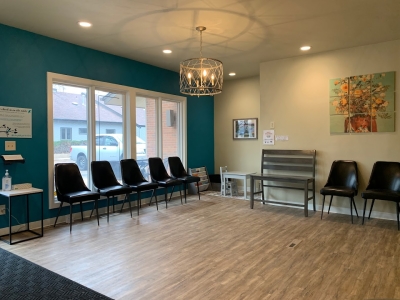 Waiting room with large windows, chairs along the wall, and wooden floor