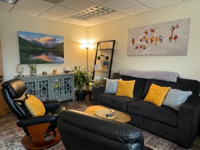 Another view of therapy office with sofa and two chairs, floor lamp, and pictures on the wall