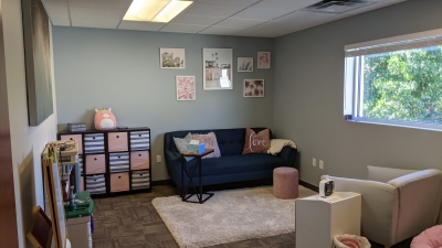 Office with a window, sofa and chair, bookcase with colorful cubbies