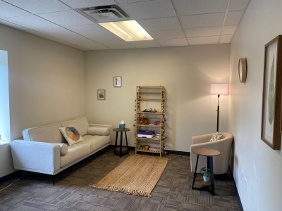 Office with sofa and comfortable chair, window, floor lamp, and bookcase