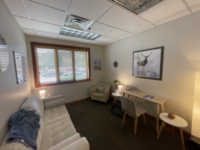 Office with sofa and comfortable chair, large windows, and a desk