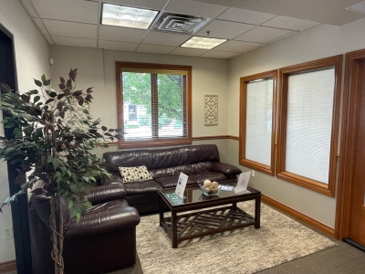 Waiting room with sofa and chair, coffee table, and windows.