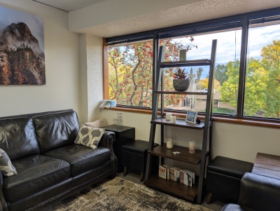 Another view of office with view out windows, sofa, and display shelves