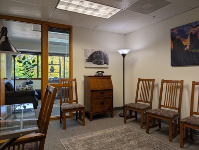 Waiting area with chairs along the wall, floor lamp, and a small desk with chair