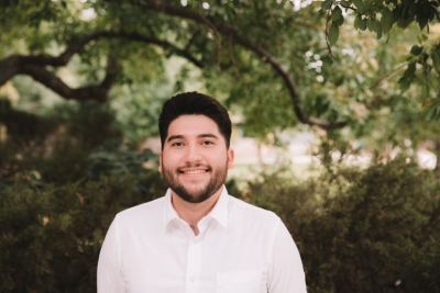Amaury Rodriguez, licensed professional counselor candidate, smiling, wearing a white button-up shirt with trees in the background.