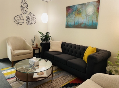 Waiting room at Bloom Counseling and Nutrition, with sofa, comfortable chairs, a glass-topped coffee table, and plants