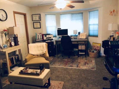 View of office showing comfortable chair, a desk, and large windows