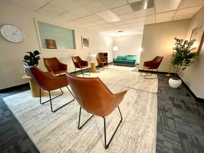 Waiting room with chairs, several plants, and area rugs