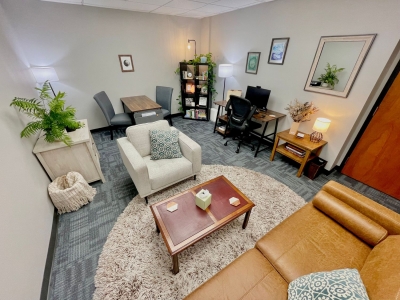 Bright office with sofa, comfortable chair, coffee table, desk, and bookcase