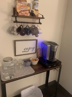 Beverage station in the waiting room, with coffee, water, and mugs