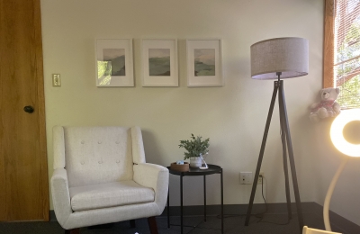 Room at Beyond the Mirror with a comfortable chair, floor lamp, side table, and window